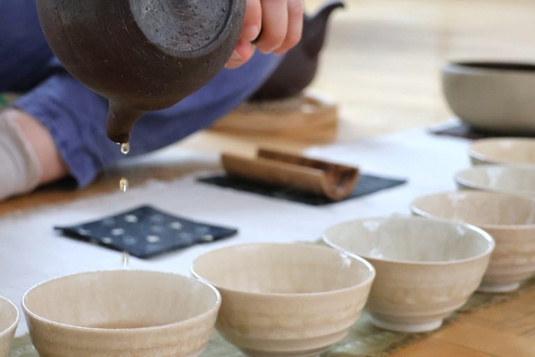 Meg smiling and holding a bowl of tea with both hands